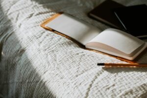 An open book sitting on top of a bed next to a pencil